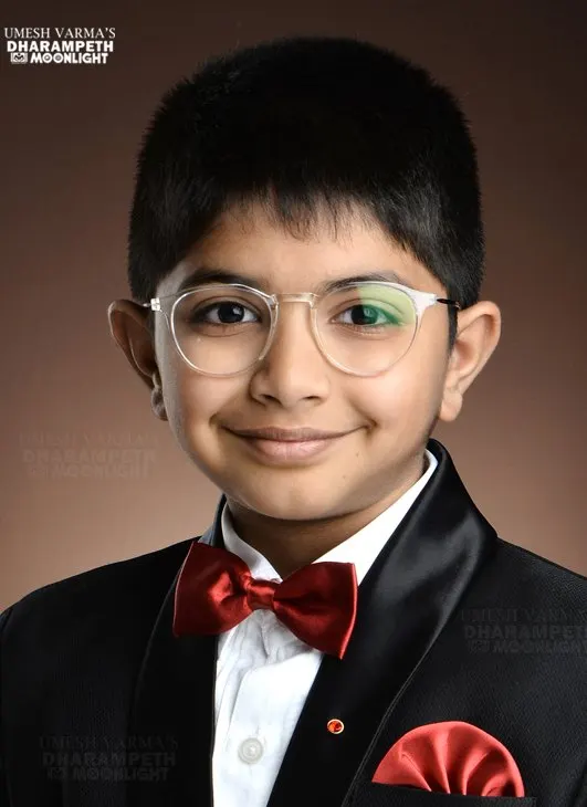 Boy in glasses wearing a tuxedo and red bow tie