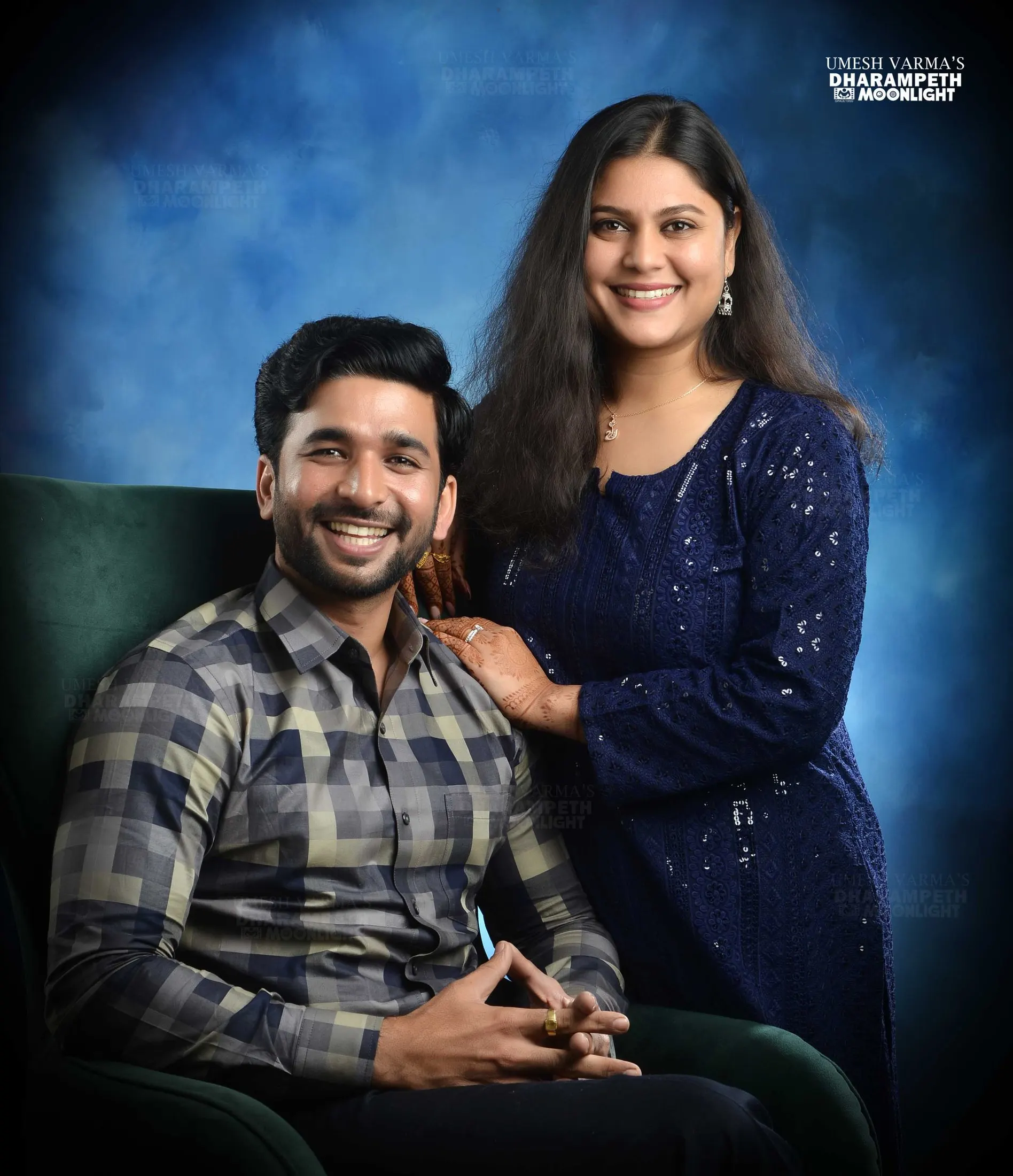 Couple posed with the husband seated in a green armchair