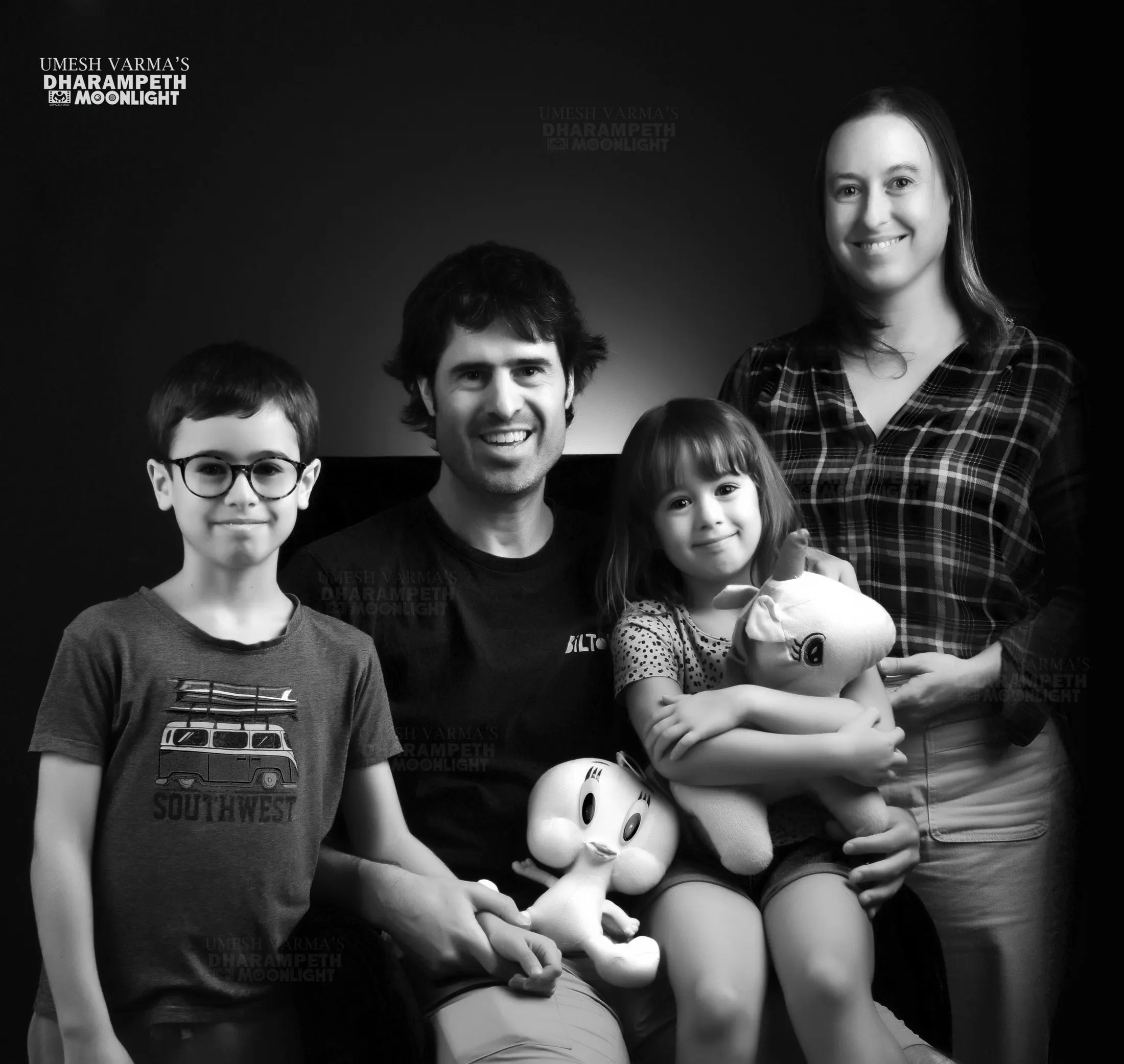 Black and white family portrait of parents with two children and soft toys