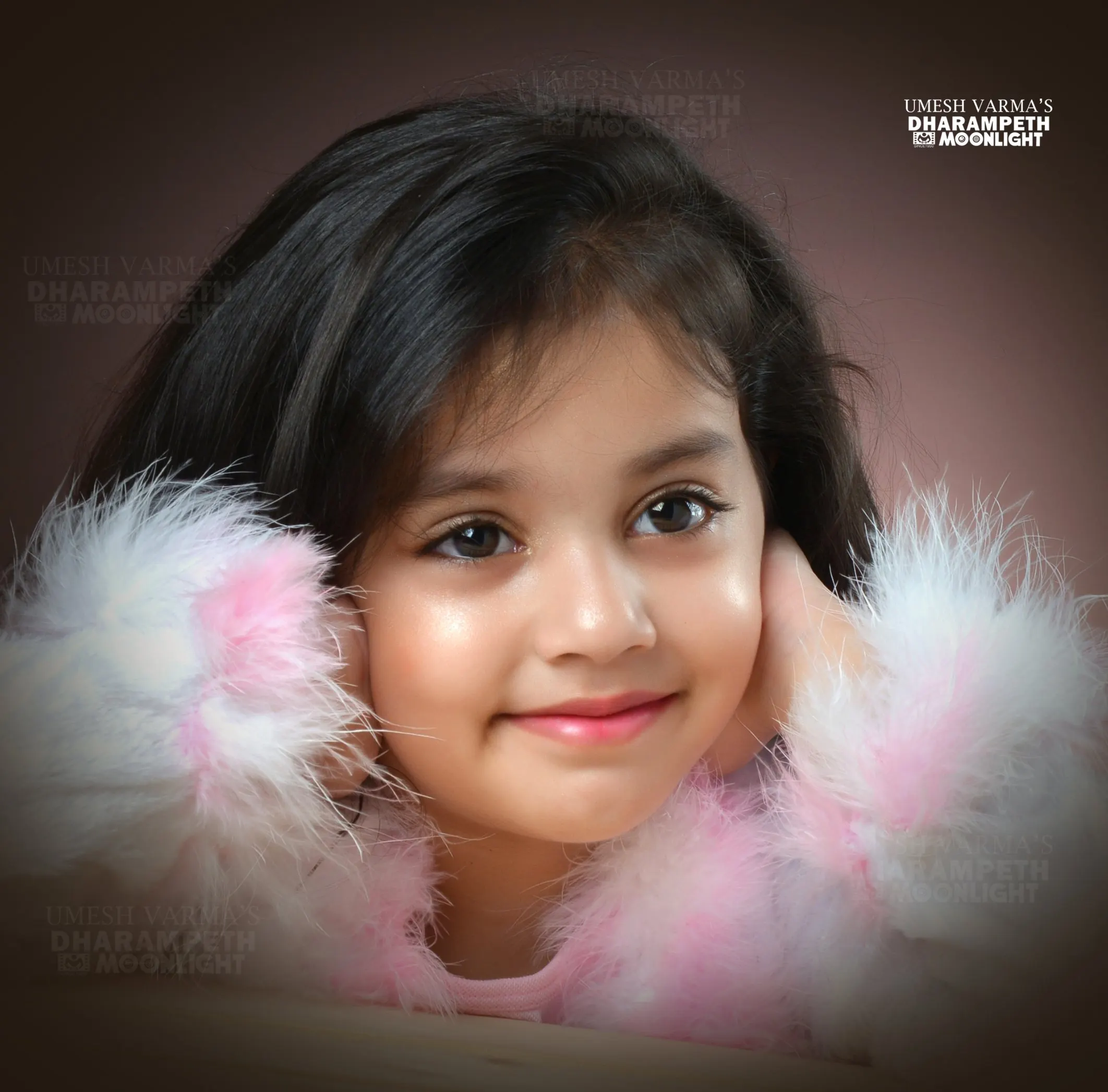 Young girl framed by soft pink feathers