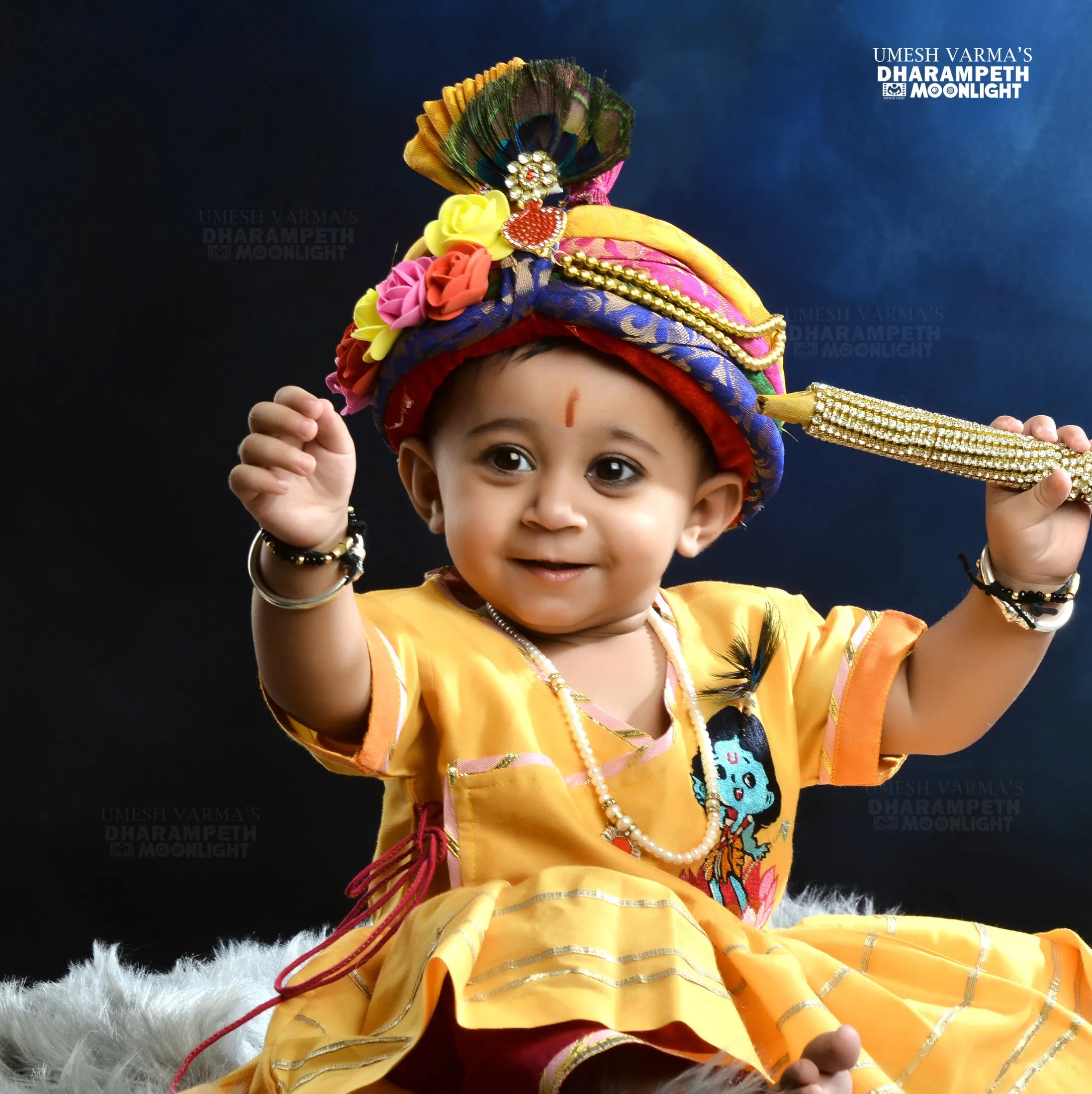 Baby in a Krishna costume with a peacock-feather turban