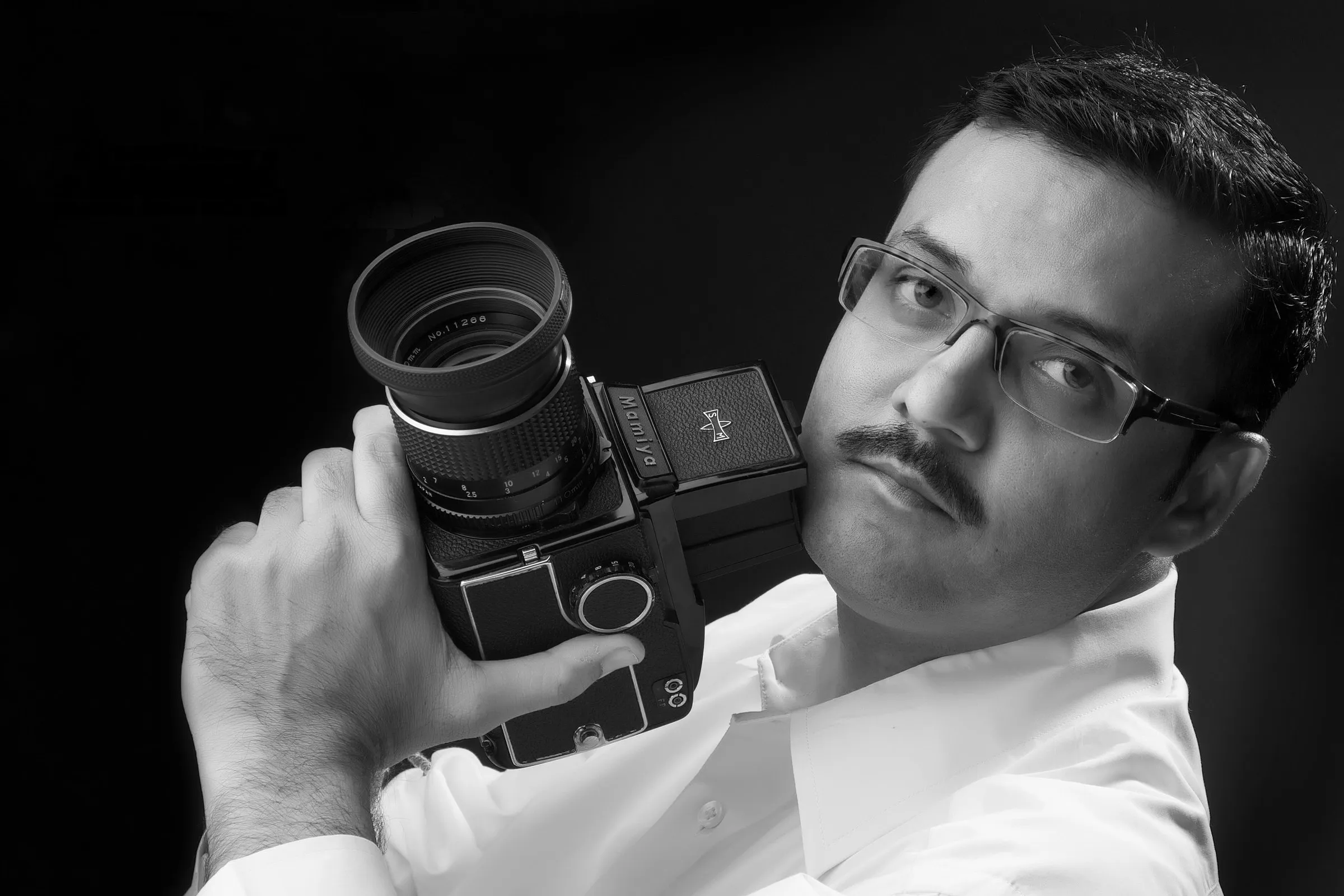 Umesh Varma holding a medium-format Mamiya camera at the studio