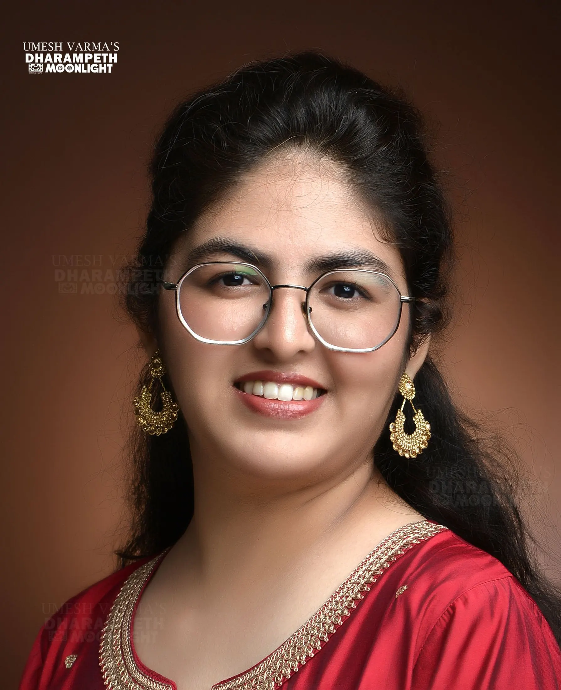 Smiling woman with round glasses and gold earrings